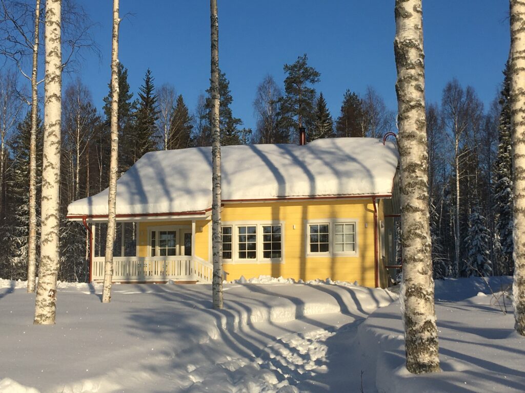 Schneebedecktes gelbes Holzhaus in der Sonne